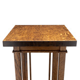 Close angled view of the plant stand’s thick square top, highlighting the richly figured oak grain, dark end grain, upper apron, and supporting posts.