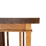 Close-up of an upper corner showing the plant stand’s thick top, oak apron, square post, slender spindle, layered rail, and precise fitted joints.