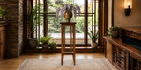Wright-inspired oak plant stand displayed before tall windows in a warm wood interior, topped with a bronze vase of cascading pale-purple flowers.