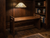 Gustav Stickley inspired Craftsman style wood bench in a warm library nook with dark wood paneling, built-in bookshelves, and stained glass pendant lighting.