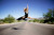 Female dancer leaping in the air in the middle of a road with flowing blonde hair and black dress