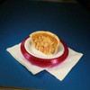 Cajun Original Mini Shrimp 15pk 5in BULK, close-up of a partially eaten mini shrimp pastry on a red plate with a white napkin against a dark background.