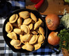 Mrs Wheat's Mini Spicy Meat Pies 100ct 1oz, a skillet filled with small, golden, baked meat pies on a checkered tablecloth.