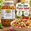 Boscoli Italian Olive Salad 128oz, large jar of mixed olives and vegetables beside a bowl of pasta salad, promoting zesty flavor and catering use.
