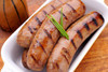 Broussard's Bayou Broussards Bayou Company Crawfish Boudin 1lb, cooked grilled sausages with grill marks garnished with fresh green chives in a white dish.