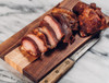 The Best Stop Pork Tasso 16oz, sliced and cooked pork tasso on a wooden cutting board.