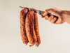 The Best Stop Andouille 24oz, smoked and dried andouille sausage being held with a knife in a hand.