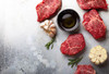 8oz Angus Beef Filet (Pack of 2), raw marbled beef steaks with garlic, rosemary, and olive oil on a gray textured surface.