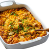 Carnival Cornbread Dressing 4lb, baked cornbread stuffing topped with chopped herbs in a white casserole dish.
