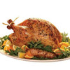 Herb Roasted Turkey 10 - 12lb, whole roasted turkey garnished with fresh herbs, lemon slices, and surrounded by greens on a white platter.