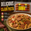 Savoies Smoked Chicken Andouille Sausage 14oz, packaged smoked sausage with a plate of Cajun pasta with sausage slices, creamy sauce, and vegetables, served on a rustic plate.