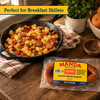 Manda Queso Smoked Sausage 12oz, spicy smoked sausage in packaging placed on a wooden table with cooked breakfast skillet containing sausage, potatoes, and vegetables.