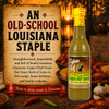 Cajun Chef Green Louisiana Hot Sauce 12oz, bottle with yellow cap and label featuring the Cajun Chef logo and Louisiana branding, placed in front of a scenic sunset background with crawfish, garlic, and spices for flavor.