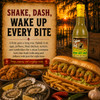 Cajun Chef Green Louisiana Hot Sauce 12oz, a glass bottle with a yellow label and red cap, set against a scenic sunset background with a picnic table, foods, and a lakeside view.