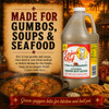 Cajun Chef Green Louisiana Hot Sauce 128oz, large plastic bottle with yellow label featuring a chef illustration, placed near a bowl of gumbo, fried seafood, and boiled shrimp, with a sunset background and decorative sign.