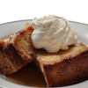 King Creole Bread Pudding 4lb, close-up of a slice of warm bread pudding topped with whipped cream on a white plate.