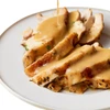 King Creole Southern Turkey Gravy 4lb, sliced turkey with creamy gravy poured over it on a white plate.