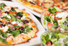 Central Grocery’s Legendary Muffuletta Olive Salad - 16oz Proprietary Recipe, close-up of a sliced pizza with olive salad topping and green salads in bowls.