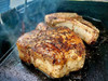 Comeaux's Stuffed Pork Chops with Pork Dressing, sizzling pork chops cooking on a cast iron skillet with a golden crispy crust.