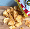 Zapp's Cajun Crawtator Chips 2oz, spicy seasoned potato chips spilling out of a bag onto a wooden surface.