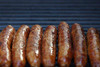Poche's Poches Bridge Hot Sausage 3lb, cooked sausages grilling on a barbecue grill.