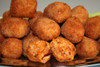 Cajun Original Crawfish Boudin Balls, 144 Balls, served on a platter with one halved to show the filling of crawfish and spices.