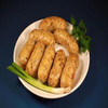 Cajun Original Crawfish Party Link 1lb, cooked crawfish sausages served on a white oval dish with green onion garnishes and fresh herbs, dark blue background.