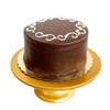 Gambino's Chocolate Doberge Cake, a rich multi-layered chocolate dessert covered in glossy chocolate icing with decorative white icing accents on top, displayed on a gold cake stand.
