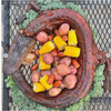 Creole Foods of Louisiana Whole Skinned Alligator Extra Large 20+ lbs, cooked alligator with corn, potatoes, and vegetables in a serving dish.