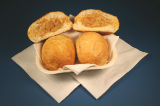 Cajun Original Shrimp Pistolettes 6pk, golden fried fritters filled with shrimp, served in a paper tray with napkins on dark background.