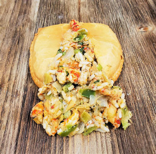 Mrs Wheat's Crawfish Pies 48ct 3.5oz, cut open to reveal crawfish, vegetables, and filling inside a flaky pastry shell on a wooden surface.
