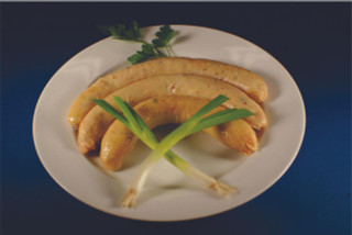 Cajun Original Shrimp Boudin 1lb, cooked shrimp and rice sausage on a white plate garnished with green onions and parsley.