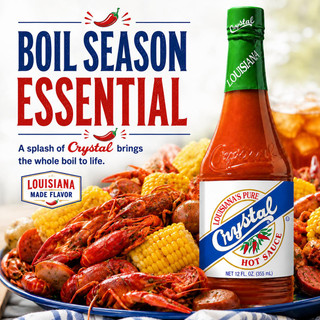 Crystal Hot Sauce 12oz, bottle of hot sauce with Louisiana flavor label surrounded by crawfish, corn, and potatoes on a platter.