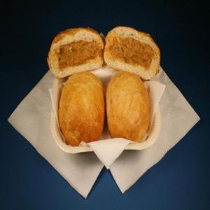 Cajun Original Alligator Pistolettes 24 Pack, three golden-brown alligator sausage-filled pastries on a white napkin with one cut in half showing the spicy filling inside.