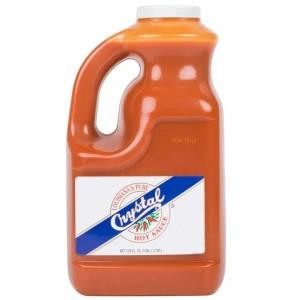 Crystal Hot Sauce 128oz, large orange plastic bottle with handle and white cap, featuring a label with the Crystal logo and blue stripe.