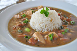 Broussard's Bayou Broussards Bayou Company Chicken & Andouille Gumbo, served with a mound of rice garnished with a sprig of parsley.