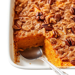 Creole Foods of Louisiana Cornbread Turducken Roll Family Feast, close-up of a savory baked turducken roll with cornbread, topped with pecans, in a white serving dish with a silver spoon.