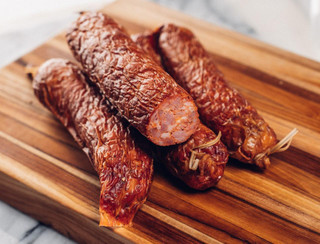 The Best Stop Andouille 24oz, grilled smoked sausage links on wooden cutting board.