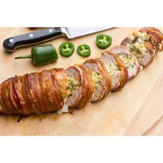 Big Easy Foods Bacon Wrapped Jalapenos with Pork Boudin, sliced and served on a wooden cutting board with chopped jalapenos and a green pepper nearby.