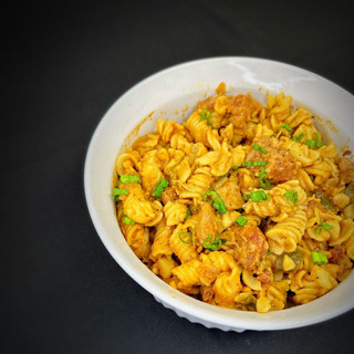 Carnival Cajun Pastalaya 4lb, a bowl of flavorful Cajun-style pasta with seasoned pasta, chunks of meat, and garnished with chopped green onions.