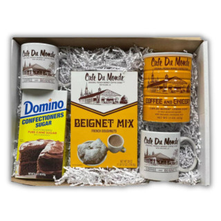 Cafe Du Monde Beignet and Coffee Gift Box, a collection of Cafe Du Monde branded products including a beignet mix, coffee beans, sugar, and two branded mugs, all arranged in a gift box with white shredded paper.