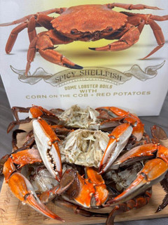 Sal's Riverside Seafood Crab, fresh cooked crabs from Sal's Riverside Gumbo with 2 pounds of crabs, served on a wooden board with crab shell halves in the foreground and seafood packaging in the background.
