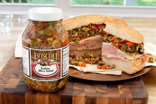 Boscoli Foods Boscoli Italian Olive Salad 32oz, jar of seasoned olive salad next to a hearty sandwich with olive salad filling on a cutting board.