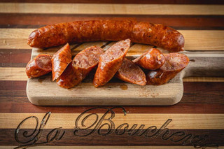 La Boucherie Smoked Andouille Sausage 16 oz, sliced smoked andouille sausage on a wooden cutting board.