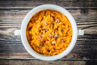 La Boucherie Sweet Potato Casserole Side Dish 2 lb, a bowl of baked sweet potato casserole topped with chopped nuts on a rustic wooden table.