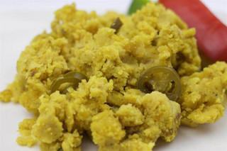 La Boucherie Jalapeno Cornbread Dressing 2 lb, close-up of yellow cornbread stuffing with jalapeño slices on a white plate.