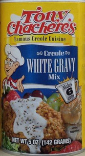 Tony Chachere's Instant White Gravy Mix 5oz, package featuring a cartoon chef and images of prepared gravy served over fried chicken and vegetables.