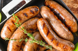 Poche's Poches DiMaggio's Italian Sausage 1lb, cooked sausages with grill marks garnished with fresh herbs on a black tray.