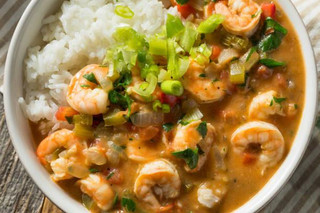 Poche's Poches Shrimp Etouffee 2lb with rice, shrimp in rich sauce topped with chopped green onions in a white bowl.