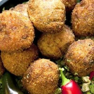 Comeaux's Boudin Balls Pork 144 Ct, close-up of breaded and fried pork boudin balls on a platter with garnishes.